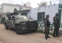 Militares con armas largas custodian a comprador de ropa en Kimbilá